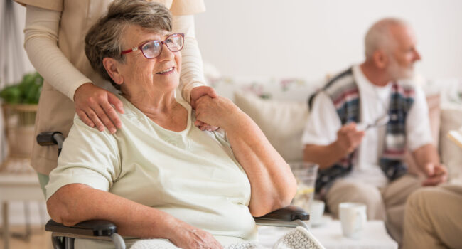 Happy senior lady sitting at wheelchair in nursing home for elderly
